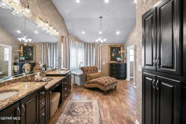 12081 E Paseo De Amor Ln E, El Paso, TX 79936 - bathroom featuring a chandelier, wallpapered walls, lofted ceiling, wood-type flooring, and a freestanding bath