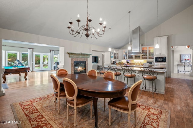 12081 E Paseo De Amor Ln E, El Paso, TX 79936 - dining space with high vaulted ceiling, a chandelier, wood finished floors, a glass covered fireplace, and pool table