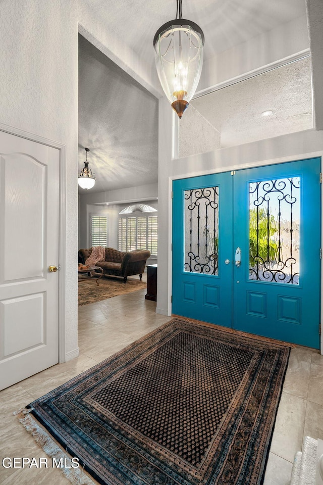 12081 E Paseo De Amor Ln E, El Paso, TX 79936 - foyer entrance featuring french doors, a textured ceiling, a chandelier, and lofted ceiling