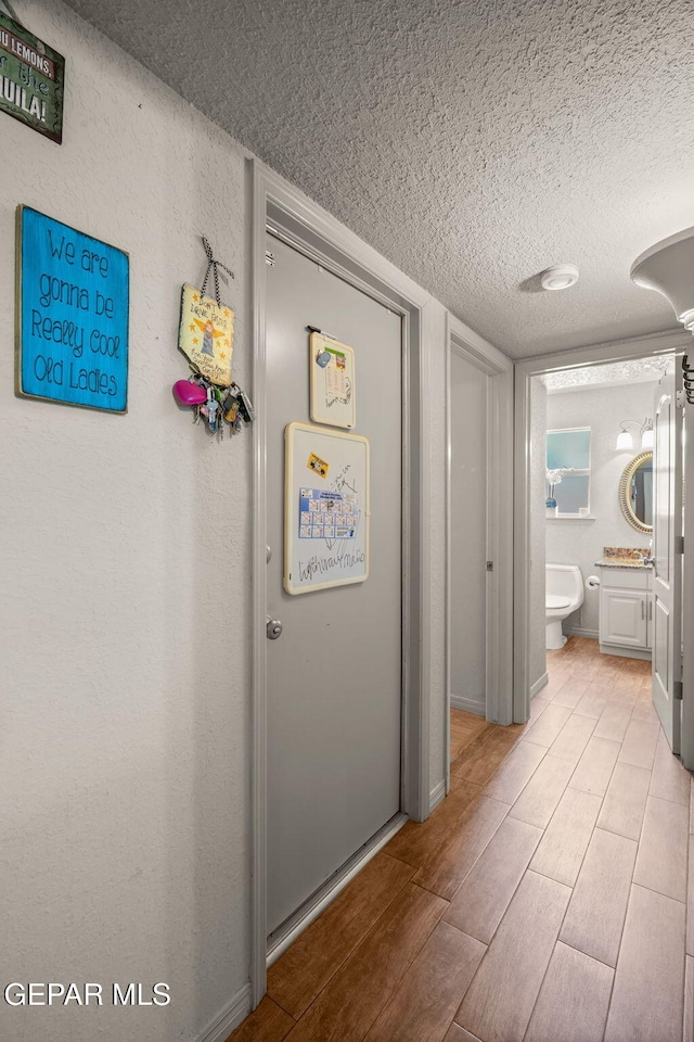 12081 E Paseo De Amor Ln E, El Paso, TX 79936 - corridor featuring a textured ceiling and wood finished floors
