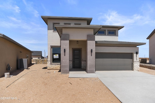 10700 Elise St, El Paso, TX 79924 - view of front of house featuring stone siding, concrete driveway, central AC, stucco siding, and an attached garage