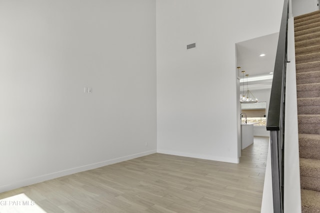 10700 Elise St, El Paso, TX 79924 - spare room with stairs, light wood-style floors, baseboards, a high ceiling, and a chandelier