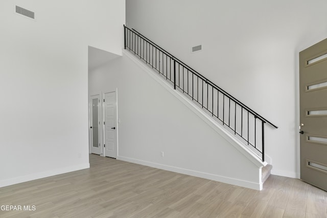 10700 Elise St, El Paso, TX 79924 - unfurnished living room featuring a towering ceiling, light wood finished floors, stairway, and baseboards