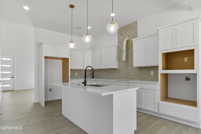 10700 Elise St, El Paso, TX 79924 - kitchen with a sink, an island with sink, decorative backsplash, white cabinetry, and light wood finished floors