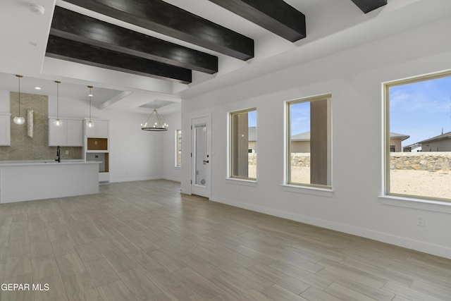 10700 Elise St, El Paso, TX 79924 - unfurnished living room featuring beam ceiling, a chandelier, baseboards, light wood-style floors, and a sink