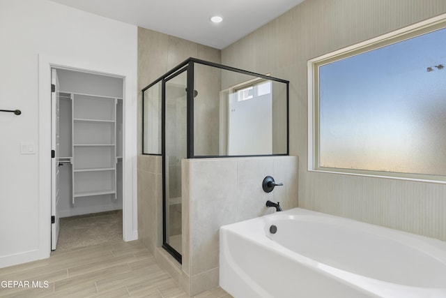 10700 Elise St, El Paso, TX 79924 - bathroom with a garden tub, a shower stall, a spacious closet, wood finished floors, and baseboards