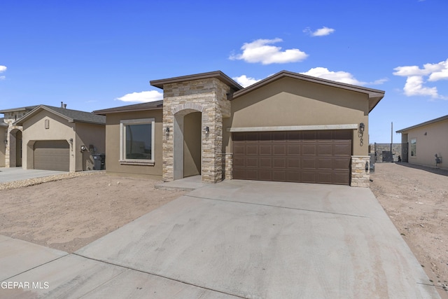 view of front of property with stucco siding, stone siding, a garage, and driveway