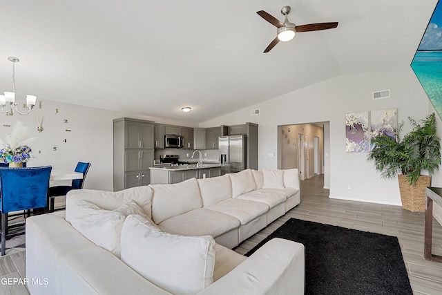 13804 Flora Vista Ave, Horizon City, TX 79928 - living room featuring a chandelier, vaulted ceiling, ceiling fan, light wood-type flooring, and baseboards