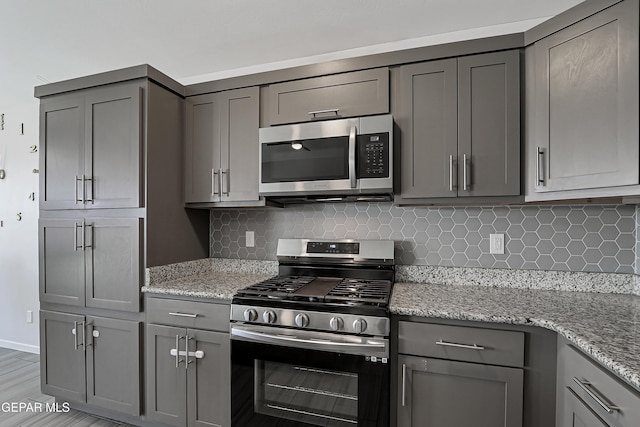 13804 Flora Vista Ave, Horizon City, TX 79928 - kitchen featuring stainless steel appliances, gray cabinets, backsplash, light stone countertops, and baseboards