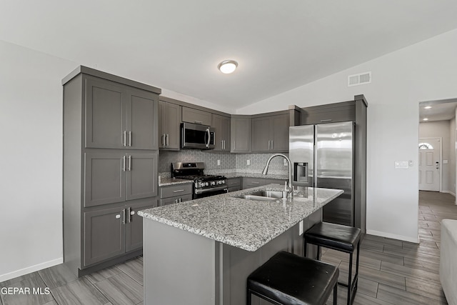 13804 Flora Vista Ave, Horizon City, TX 79928 - kitchen with appliances with stainless steel finishes, a sink, gray cabinetry, light stone counters, and vaulted ceiling
