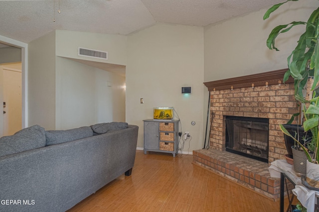 1662 Gene Torres Dr, El Paso, TX 79936 - living area featuring lofted ceiling, wood finished floors, a textured ceiling, and a brick fireplace