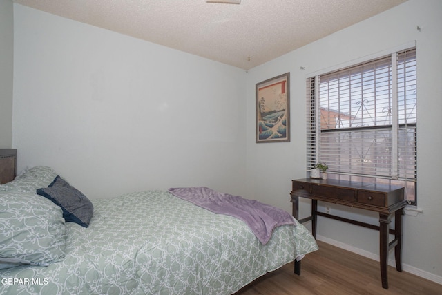 1662 Gene Torres Dr, El Paso, TX 79936 - bedroom with wood finished floors, baseboards, and a textured ceiling