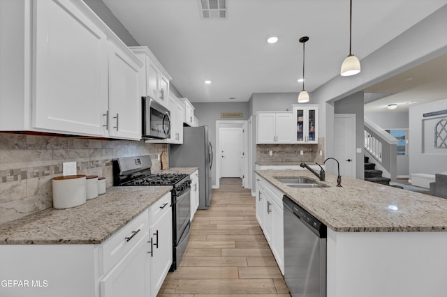 14953 Willie Worsley Ave, El Paso, TX 79938 - kitchen with appliances with stainless steel finishes, a sink, light wood-style flooring, backsplash, and an island with sink