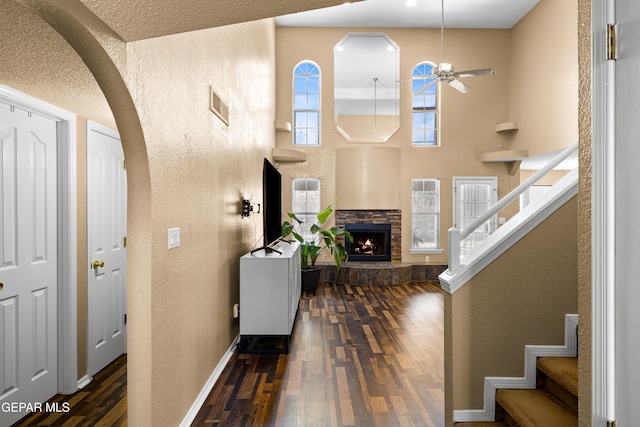 7107 Desert Jewel Dr, El Paso, TX 79912 - entrance foyer with a textured wall, dark wood-style flooring, arched walkways, stairs, and a fireplace