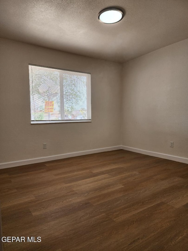 301 Bandolina Dr, Socorro, TX 79927 - empty room with dark wood finished floors, baseboards, and a textured ceiling