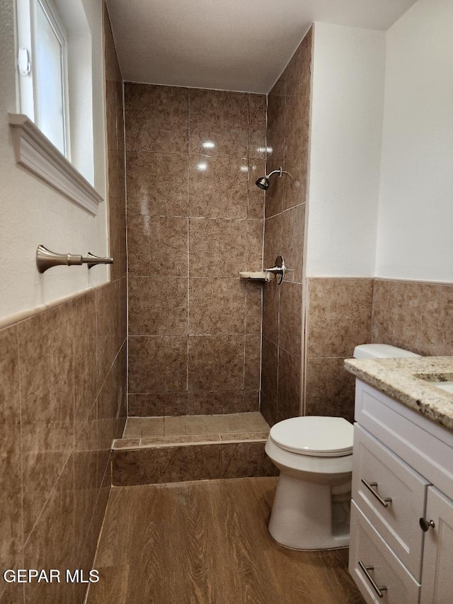 301 Bandolina Dr, Socorro, TX 79927 - bathroom with tile walls, toilet, a tile shower, wood finished floors, and vanity