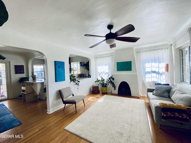 910 Mesita Dr, El Paso, TX 79902 - living area with arched walkways, a ceiling fan, wood finished floors, and a fireplace with flush hearth