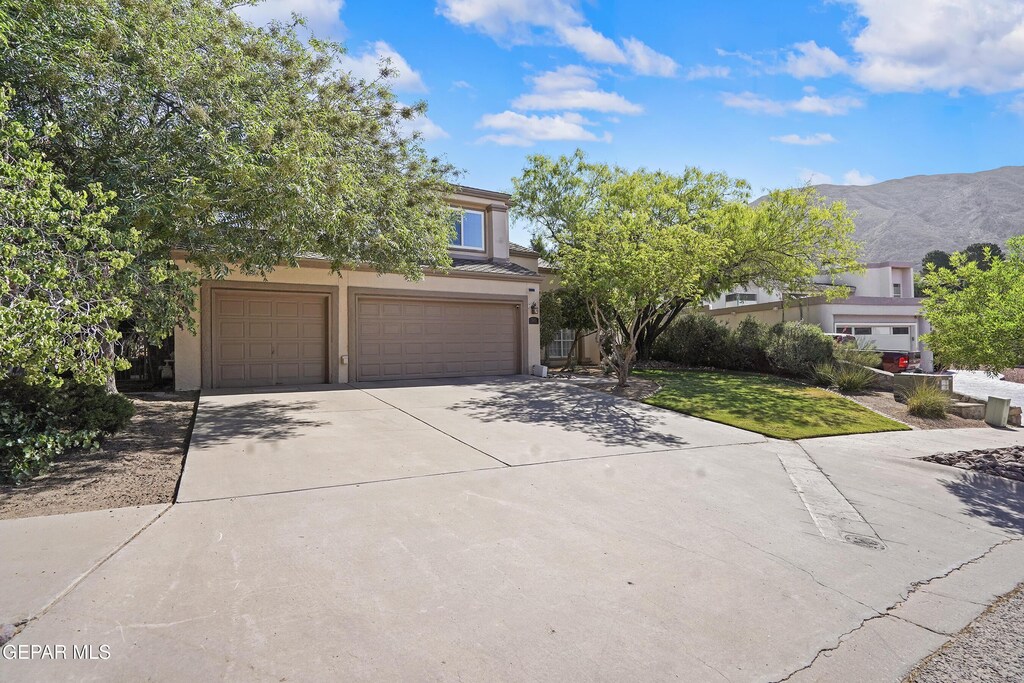 505 Canyon Springs Dr, El Paso, TX 79912 - obstructed view of property featuring driveway, an attached garage, stucco siding, and a mountain view