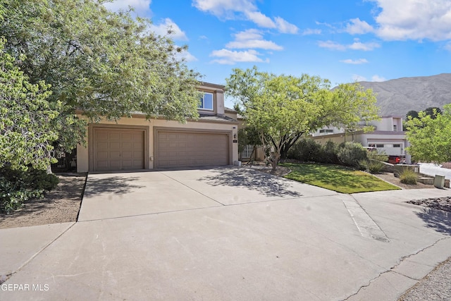505 Canyon Springs Dr, El Paso, TX 79912 - obstructed view of property featuring driveway, an attached garage, stucco siding, and a mountain view