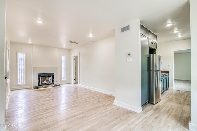 2300 N Campbell St, El Paso, TX 79902 - unfurnished living room with light wood-style flooring, recessed lighting, and a fireplace with raised hearth