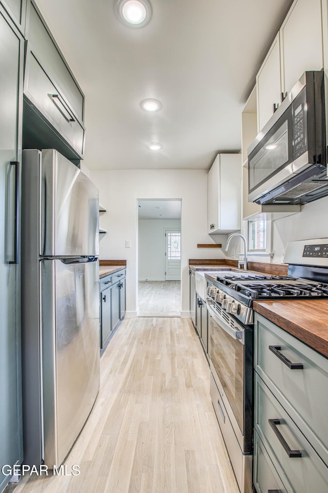 2300 N Campbell St, El Paso, TX 79902 - kitchen with stainless steel appliances, butcher block countertops, open shelves, light wood-style floors, and white cabinets
