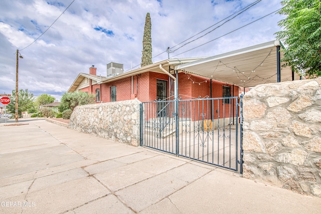2300 N Campbell St, El Paso, TX 79902 - view of side of home featuring a gate, brick siding, a chimney, and a carport