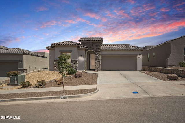 7389 Cimarron Gap Dr, El Paso, TX 79911 - mediterranean / spanish-style home with a tiled roof, an attached garage, stucco siding, driveway, and stone siding