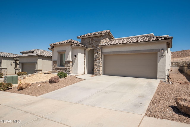 7389 Cimarron Gap Dr, El Paso, TX 79911 - mediterranean / spanish house with stucco siding, an attached garage, concrete driveway, a tiled roof, and stone siding