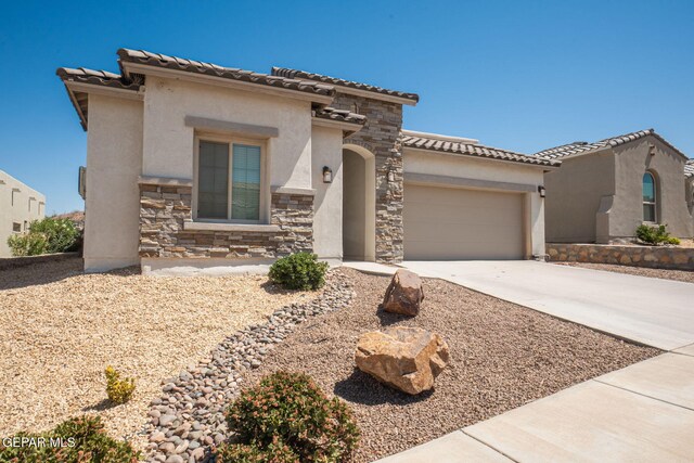 7389 Cimarron Gap Dr, El Paso, TX 79911 - mediterranean / spanish house with stucco siding, stone siding, a garage, concrete driveway, and a tile roof