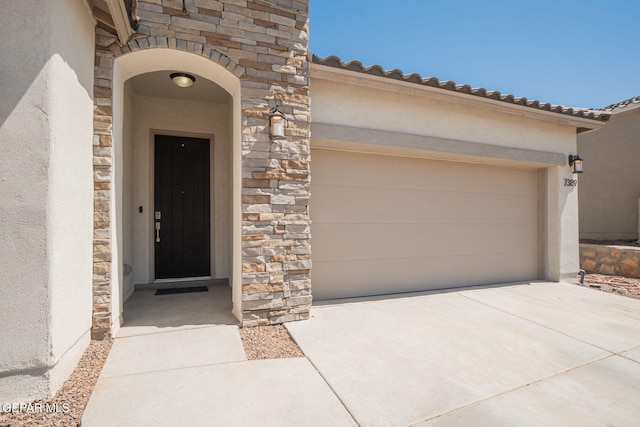 7389 Cimarron Gap Dr, El Paso, TX 79911 - property entrance featuring stone siding, concrete driveway, stucco siding, and an attached garage