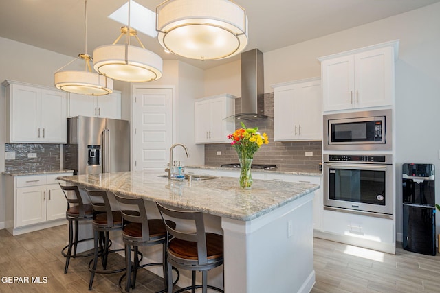 7389 Cimarron Gap Dr, El Paso, TX 79911 - kitchen featuring stainless steel appliances, wall chimney exhaust hood, a sink, and light wood-type flooring