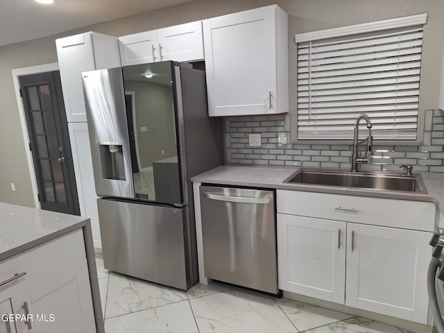 11574 La Poblana Dr, Socorro, TX 79927 - kitchen featuring appliances with stainless steel finishes, a sink, light marble finish flooring, white cabinets, and tasteful backsplash