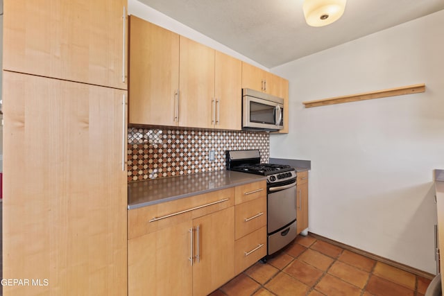 903 Agua Caliente Dr, El Paso, TX 79912 - kitchen featuring stainless steel appliances, tasteful backsplash, light brown cabinetry, baseboards, and dark countertops