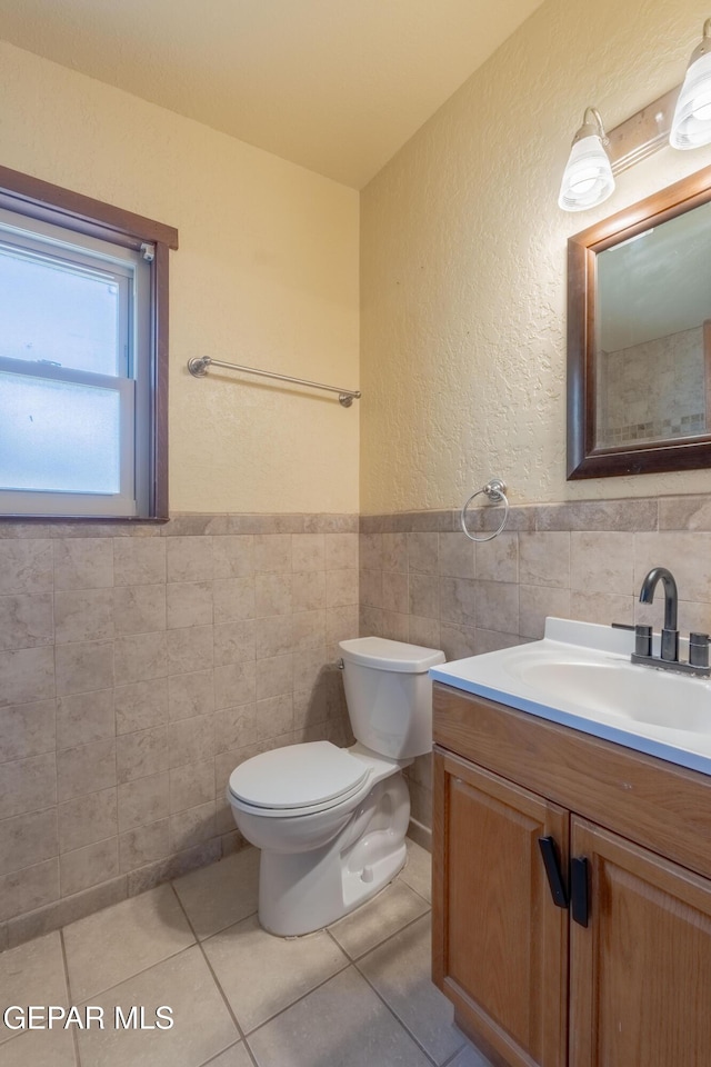 903 Agua Caliente Dr, El Paso, TX 79912 - half bath with tile walls, a textured wall, vanity, toilet, and tile patterned flooring