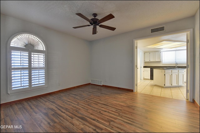 4372 Loma De Oro Dr, El Paso, TX 79934 - empty room with light wood-style floors, ceiling fan, baseboards, a sink, and a textured ceiling