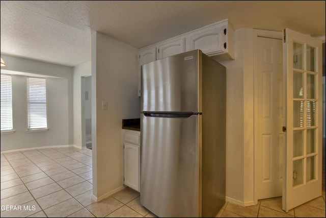 4372 Loma De Oro Dr, El Paso, TX 79934 - kitchen featuring freestanding refrigerator, light tile patterned floors, white cabinets, dark countertops, and a textured ceiling