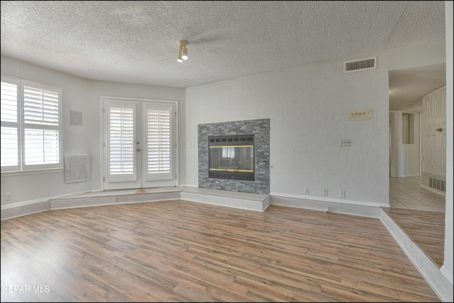 4372 Loma De Oro Dr, El Paso, TX 79934 - unfurnished living room featuring wood finished floors, a glass covered fireplace, a textured ceiling, and baseboards