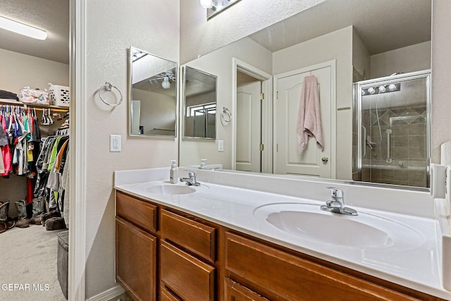 14181 Rudy Valdez Dr, El Paso, TX 79938 - full bathroom with a stall shower, double vanity, a spacious closet, and a textured wall