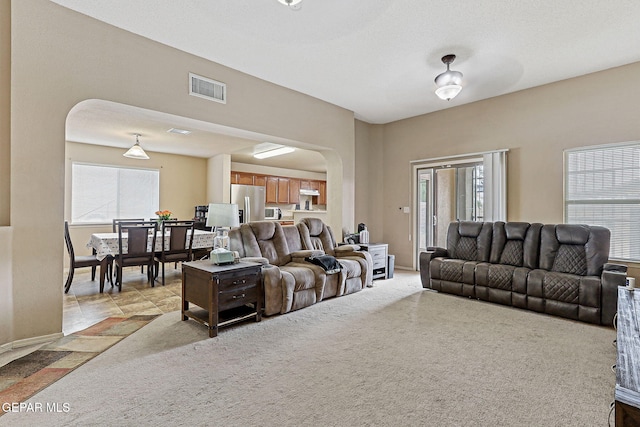 14181 Rudy Valdez Dr, El Paso, TX 79938 - living room with arched walkways, plenty of natural light, light colored carpet, and baseboards