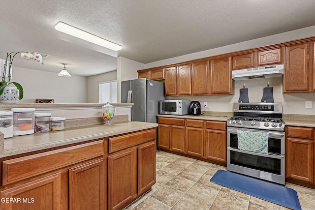 14181 Rudy Valdez Dr, El Paso, TX 79938 - kitchen featuring under cabinet range hood, stainless steel appliances, brown cabinets, a textured ceiling, and light countertops
