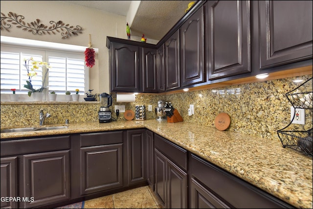 1337 Emerald Gate Ln, El Paso, TX 79936 - kitchen with decorative backsplash, a sink, dark brown cabinets, and light stone counters