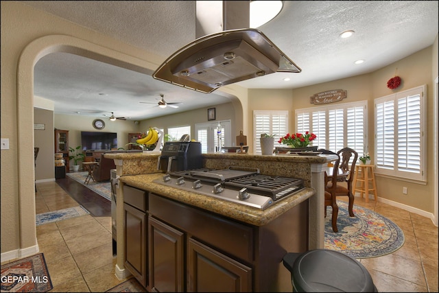 1337 Emerald Gate Ln, El Paso, TX 79936 - kitchen with a textured ceiling, stainless steel gas cooktop, a kitchen island, light tile patterned floors, and ceiling fan