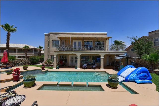 1337 Emerald Gate Ln, El Paso, TX 79936 - rear view of house featuring a balcony, french doors, a patio area, a pool with connected hot tub, and stucco siding