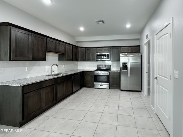 11500 Summer Dr Unit A & B, Socorro, TX 79927 - kitchen with appliances with stainless steel finishes, a sink, light stone counters, dark brown cabinetry, and light tile patterned floors