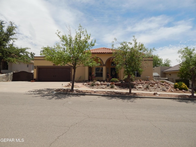 7012 Diamond Ridge Dr, El Paso, TX 79912 - mediterranean / spanish house with concrete driveway, a garage, stucco siding, and a tiled roof