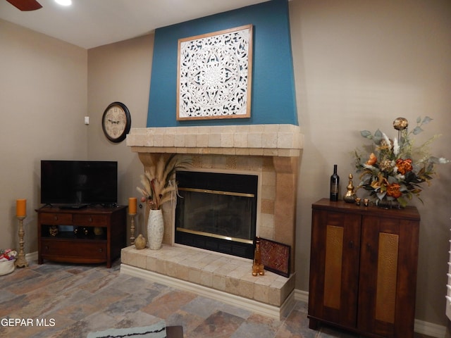 7012 Diamond Ridge Dr, El Paso, TX 79912 - living room featuring stone finish flooring, a glass covered fireplace, baseboards, and a ceiling fan