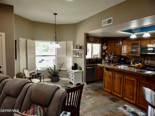 7012 Diamond Ridge Dr, El Paso, TX 79912 - kitchen with stainless steel appliances, hanging light fixtures, brown cabinetry, and glass insert cabinets