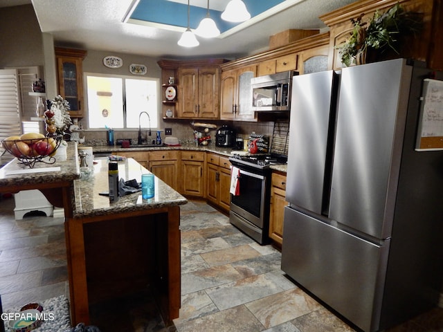 7012 Diamond Ridge Dr, El Paso, TX 79912 - kitchen with appliances with stainless steel finishes, stone tile flooring, a sink, backsplash, and light stone counters