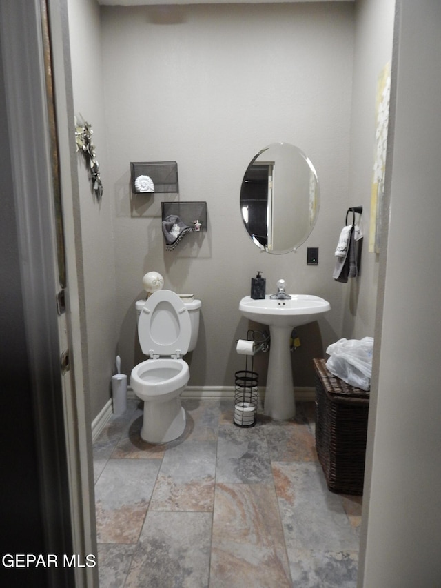 7012 Diamond Ridge Dr, El Paso, TX 79912 - half bathroom featuring baseboards, toilet, stone finish flooring, and a sink