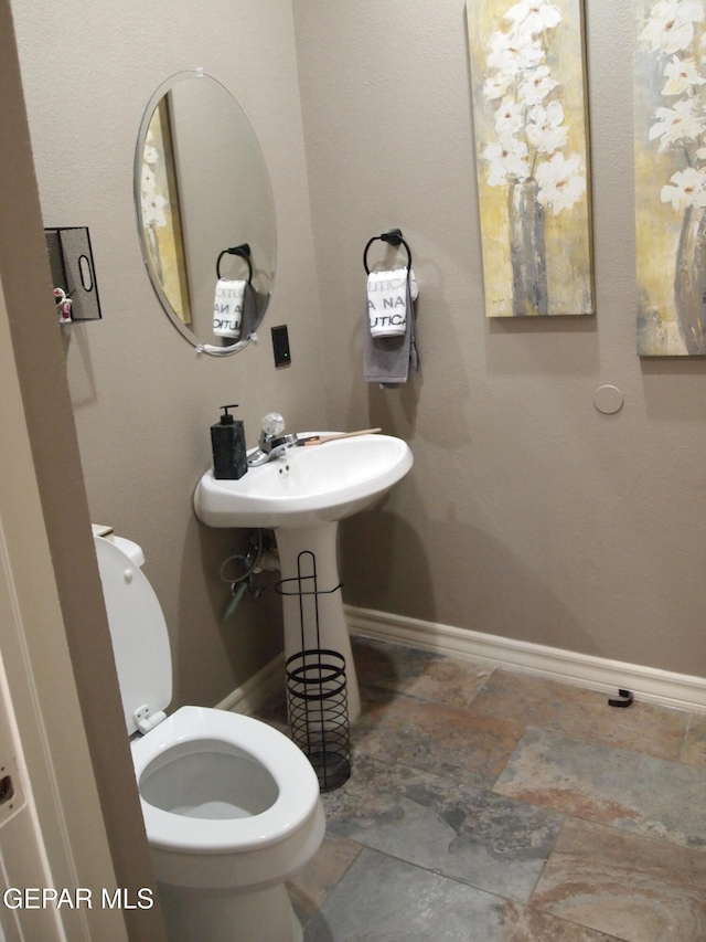 7012 Diamond Ridge Dr, El Paso, TX 79912 - half bath featuring stone finish floors, toilet, and baseboards